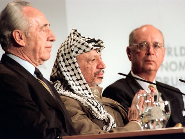 Beim WEF 1994 sitzt der damalige israelische Aussenminister Shimon Peres (links) an einem Tisch mit Palästinenserführer Jassir Afafat (Mitte). Hinten: WEF-Gründer Klaus Schwab.