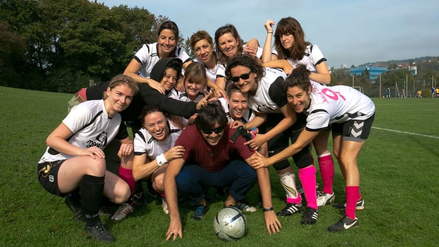 Die Fussballerinnen posieren um einen Mann mit Ball herum. Die Fussballerinnen posieren um einen Mann mit Ball herum.