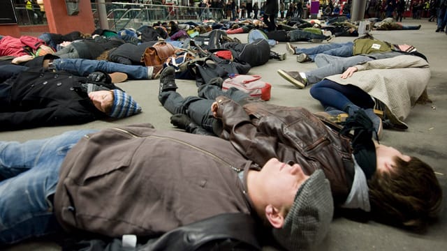 Ein Flashmob im Hauptbahnhof Bern: 50 Personen liegen auf dem Boden. Ein Flashmob im Hauptbahnhof Bern: 50 Personen liegen auf dem Boden.