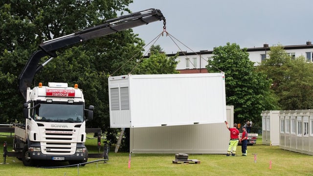 Ein Lastwagen ladet Container ab. Ein Lastwagen ladet Container ab.