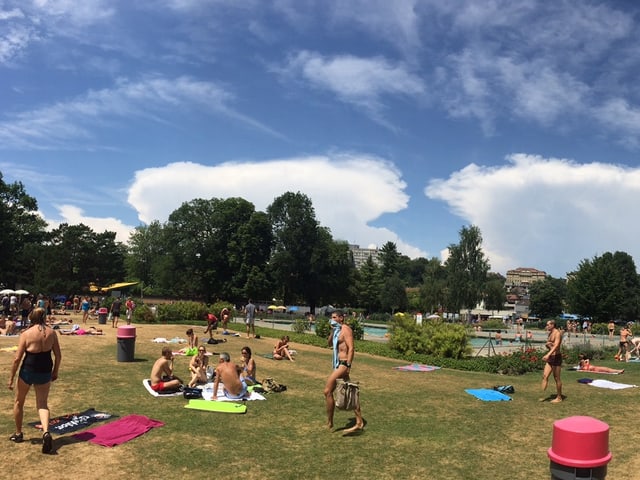 Sonniger Tag, Liegewiese mit vielen Leuten, am Horizont zwei ambossförmige Wolken. Sonniger Tag, Liegewiese mit vielen Leuten, am Horizont zwei ambossförmige Wolken.