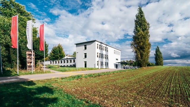 Weiss Gebäude in L-Form hinter Acker. Weiss Gebäude in L-Form hinter Acker.