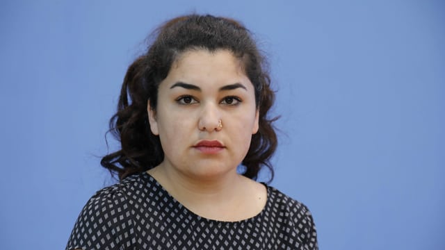 eine junge Frau schaut in die Kamera, blauer Hintergrund eine junge Frau schaut in die Kamera, blauer Hintergrund
