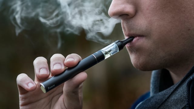 Ein Mann raucht eine E-Zigarette Ein Mann raucht eine E-Zigarette
