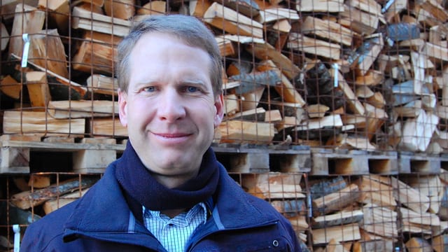 Mann vor Holzbeige. Mann vor Holzbeige.