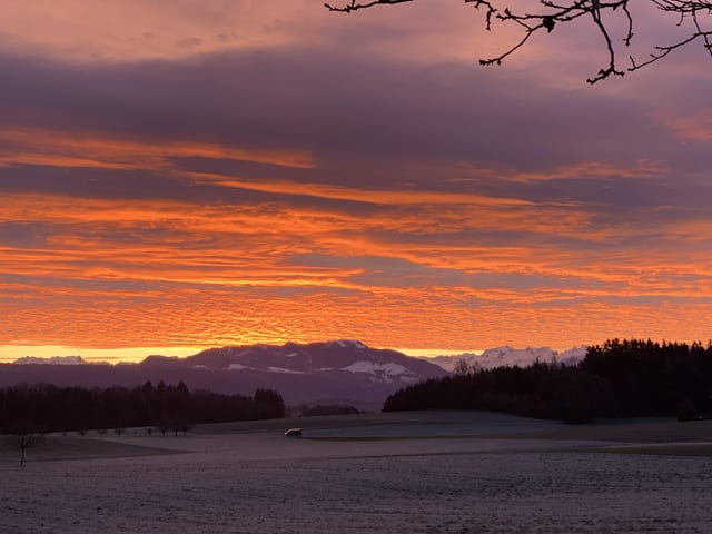 Blick auf die Alpen, oranger Himmel.