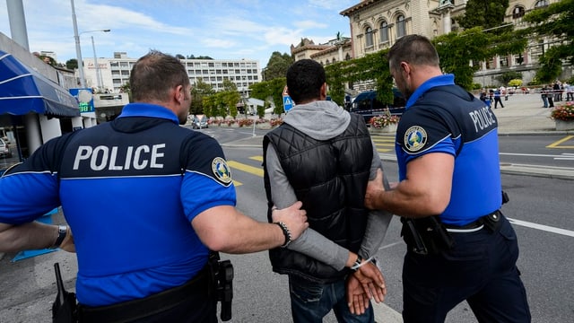 Symbolbild: Ein dunkelhäutiger Mann wird von zwei Polizisten abgeführt. Symbolbild: Ein dunkelhäutiger Mann wird von zwei Polizisten abgeführt.