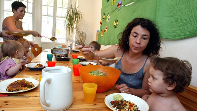 Zwei Betreuerinnen einer Kindertagesstätte mit Kindern beim Mittagessen. Zwei Betreuerinnen einer Kindertagesstätte mit Kindern beim Mittagessen.