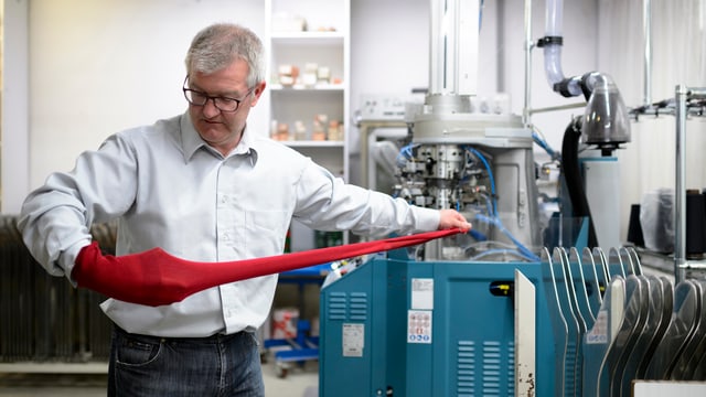 Reneé Tanner mit Sockenstoff, der aus einer Fabrikationsmaschine kommt. Reneé Tanner mit Sockenstoff, der aus einer Fabrikationsmaschine kommt.