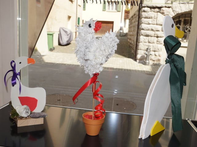 Drei Gänse aus Papier in einem Schaufenster.