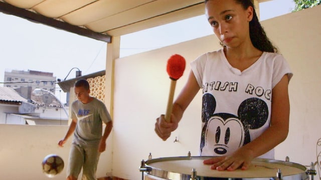 Ein Mädchen trommelt, dahinter spielt ein Junge Fussball. Ein Mädchen trommelt, dahinter spielt ein Junge Fussball.
