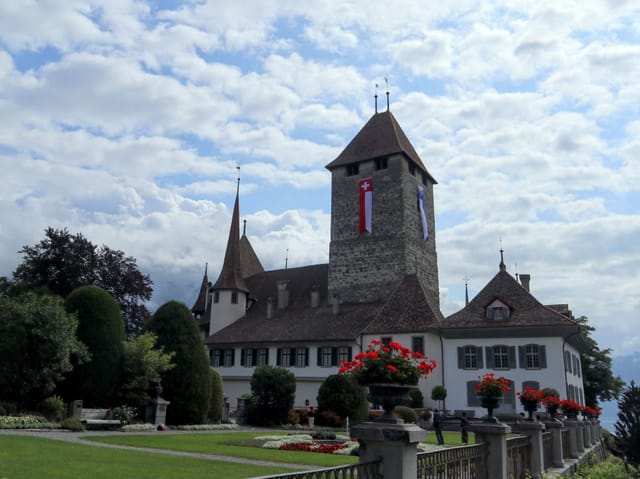 Blick auf das Schloss Spiez. Am Himmel hat es viele weisse Wolken aber auch viele blaue Lücken.