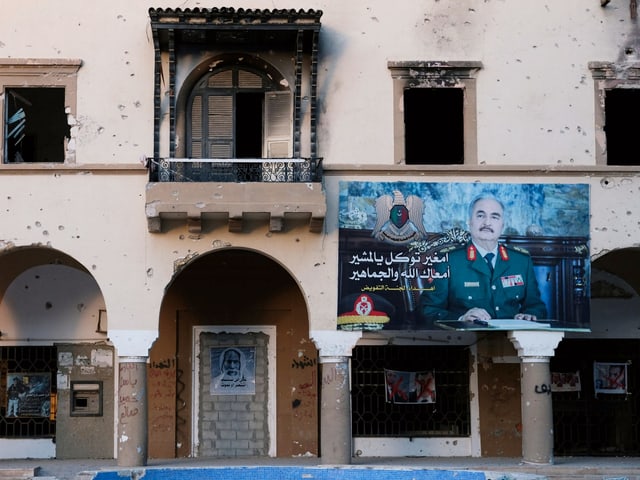 Gebäude mit Schusslöchern und ein Plakat mit Haftar Gebäude mit Schusslöchern und ein Plakat mit Haftar