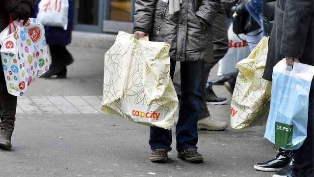 Mehrere Menschen in einer Einkaufsstrasse mit Plastiktüten. Mehrere Menschen in einer Einkaufsstrasse mit Plastiktüten.