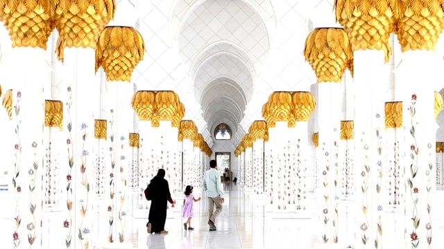 Ein Mann, eine Frau in Tschador und ein Kind laufen durch einen Gang in der Moschee. Ein Mann, eine Frau in Tschador und ein Kind laufen durch einen Gang in der Moschee.