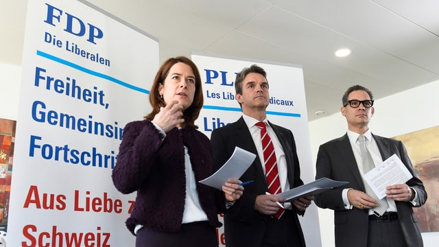 Frau und zwei Männer vor Plakaten mit Slogans der FDP. Frau und zwei Männer vor Plakaten mit Slogans der FDP.
