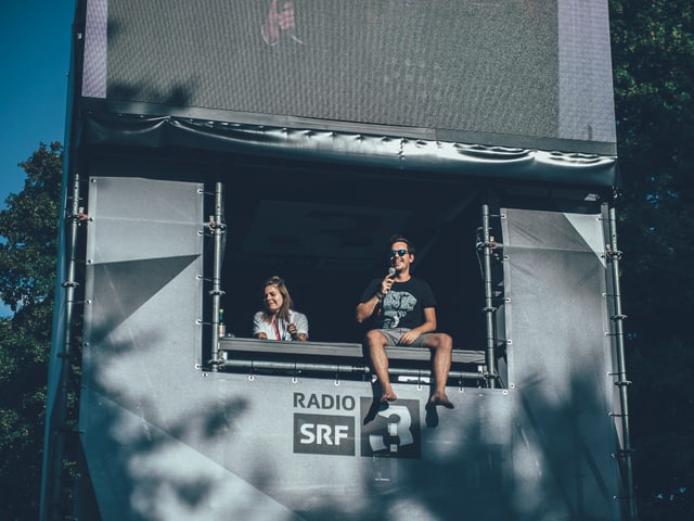 Moderator Fabio Nay begrüsst die Gurtenfestival-Besucher am Eingangs-Tower von SRF 3.
