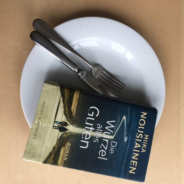 Der Roman «Die Wurzel alles Guten» liegt auf einem weissen Teller. Messer und Gabel drunter. Der Roman «Die Wurzel alles Guten» liegt auf einem weissen Teller. Messer und Gabel drunter.