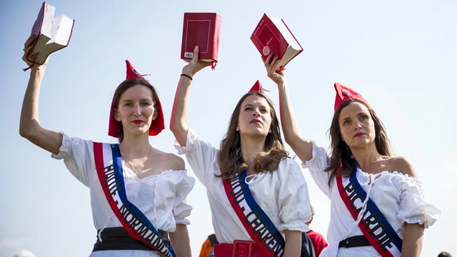 Drei Frauen als Marianne verkleidet halten jeweils das französische Gesetz in der Hand Drei Frauen als Marianne verkleidet halten jeweils das französische Gesetz in der Hand