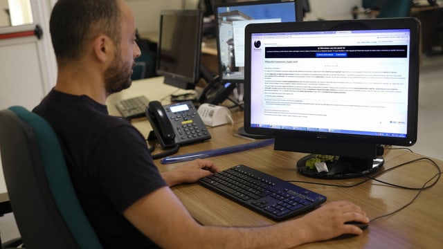 Mann sitzt vor Computer, der Wikipedia anzeigt Mann sitzt vor Computer, der Wikipedia anzeigt
