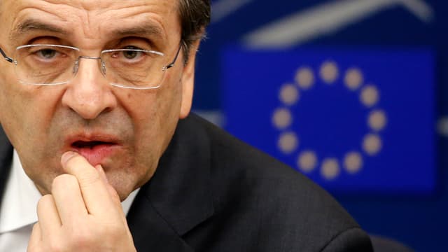 Antonis Samaras hält mit der Hand die Unterlippe und schaut in die Kamera, im Hintergrund eine EU-Flagge Antonis Samaras hält mit der Hand die Unterlippe und schaut in die Kamera, im Hintergrund eine EU-Flagge