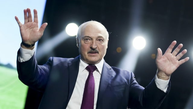 Lukaschenko hat beide Hände erhoben und blickt in die Ferne. Lukaschenko hat beide Hände erhoben und blickt in die Ferne.