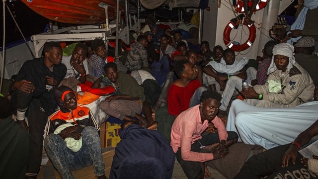 Flüchtlinge sitzen in der Nacht auf dem Schiffsdeck. Flüchtlinge sitzen in der Nacht auf dem Schiffsdeck.
