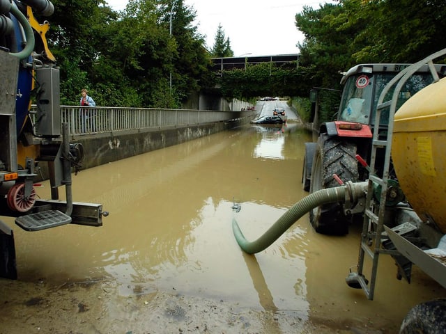 Helfer beschäftigen sich nach schweren Regenfaellen mit den Aufraeumarbeiten. Der Lyssbach hat weite Teile der Wohngebiete meterhoch überflutet. 