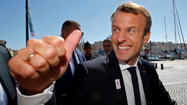 Emmanuel Macron lachend in Nahaufnahme mit hoch gerecktem Daumen. Emmanuel Macron lachend in Nahaufnahme mit hoch gerecktem Daumen.