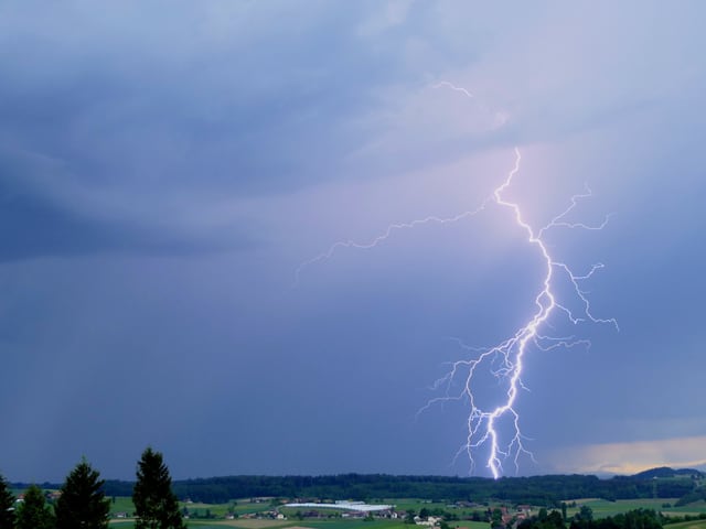 Ein Blitz zuckt aus einer dunklen Gewitterwolke.