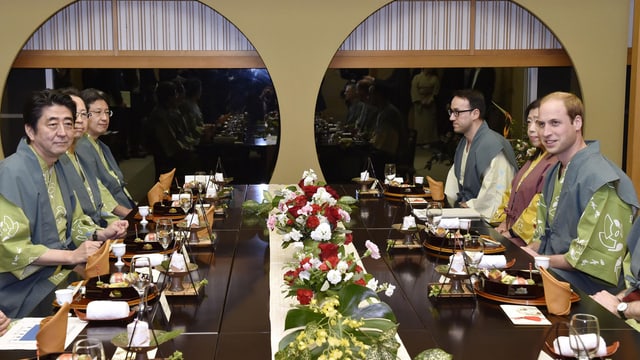Prinz William kniet mit anderen Personen an einem feierlich gedeckten Tisch im japanischen Stil. Prinz William kniet mit anderen Personen an einem feierlich gedeckten Tisch im japanischen Stil.