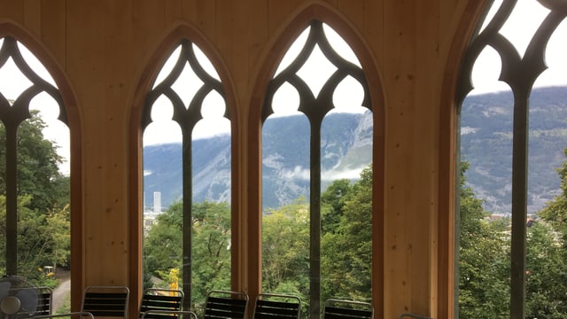 Helle Holzwände und kunstvoll gestaltete Fenster, im Pavillon stehen Stühle. Helle Holzwände und kunstvoll gestaltete Fenster, im Pavillon stehen Stühle.