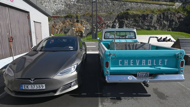 Ein Elektroauto parkt neben einem Lastauto. Ein Elektroauto parkt neben einem Lastauto.