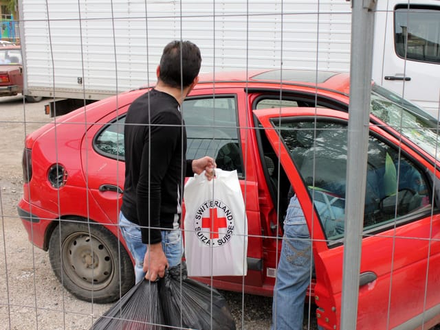 Männer laden Hilfsgüter ins Auto.