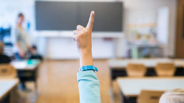 Ein Kind hebt in der Schule die Hand. Ein Kind hebt in der Schule die Hand.