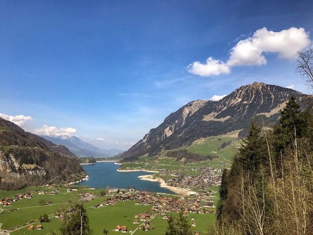 Tief blauer Himmel über dem See, über den Gipfeln Schönwetterwolken.