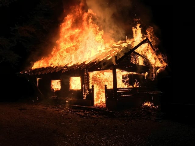 Eine Waldhütte steht mitten in der Nacht in Flammen.