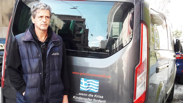 Ein Mann steht vor einem Minivan. Ein Mann steht vor einem Minivan.