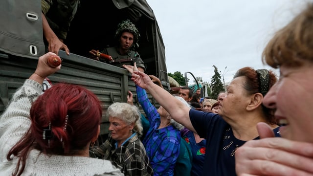 Menschen erhalten Esswaren von einem Militärtransporter Menschen erhalten Esswaren von einem Militärtransporter
