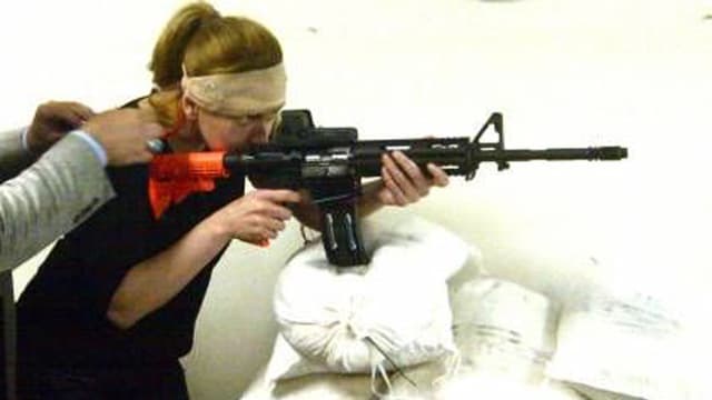 Eine Frau stützt ein Sturmgewehr auf Sandsäcken ab. Eine Frau stützt ein Sturmgewehr auf Sandsäcken ab.