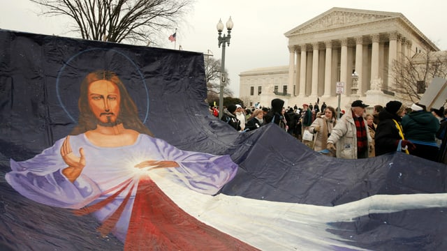 Demonstranten tragen ein grosses Tuch mit einer Jesusfigur. Demonstranten tragen ein grosses Tuch mit einer Jesusfigur.