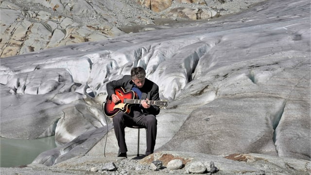 Ein Mann sitzt mit Gitarre an einem Gletscher. Ein Mann sitzt mit Gitarre an einem Gletscher.