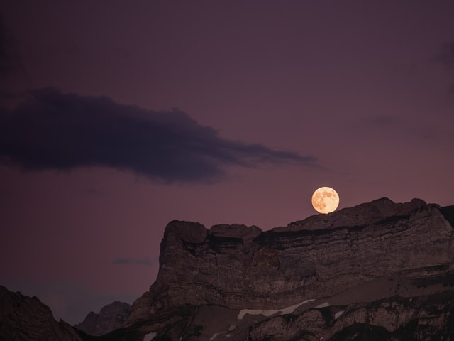 Dunkelvioletter Himmel mit Bergen im Vordergrund und grossem, leuchtendem Vollmond