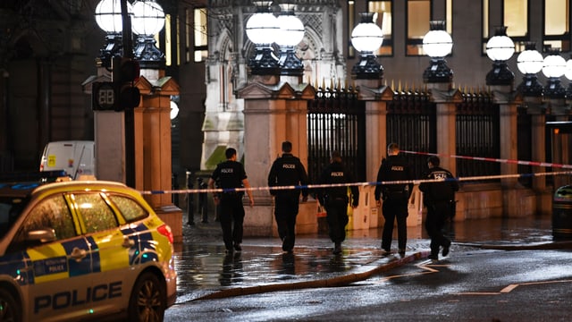 Fünf Polizisten gehen Richtung Bahnhof Charing Cross. Die Strasse hinter ihnen ist mit Absperrband gesperrt. Fünf Polizisten gehen Richtung Bahnhof Charing Cross. Die Strasse hinter ihnen ist mit Absperrband gesperrt.