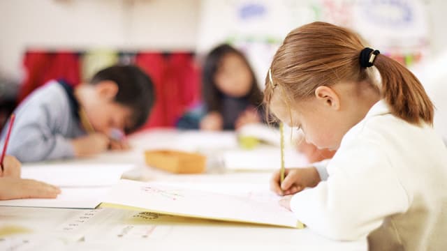 Schülerin bei Schreibarbeiten, im Hintergrund weitere Schüler Schülerin bei Schreibarbeiten, im Hintergrund weitere Schüler