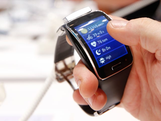 Eine Männerhand hält eine Gear S Smartwatch von Samsung. Eine Männerhand hält eine Gear S Smartwatch von Samsung.