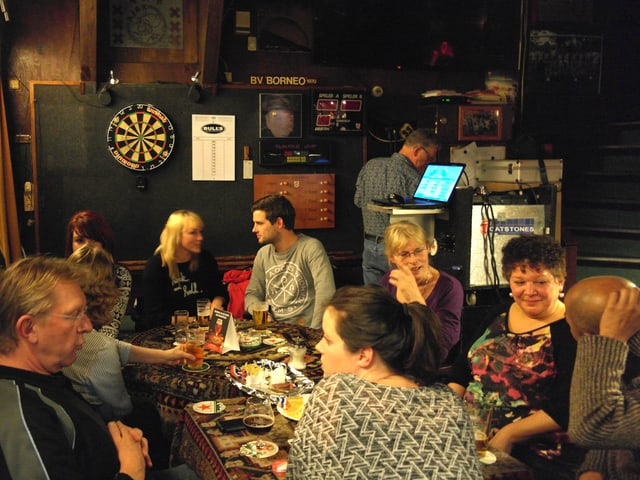In der Kneipe sitzen die Stammgäste um den Tisch und trinken Bier. In der Kneipe sitzen die Stammgäste um den Tisch und trinken Bier.