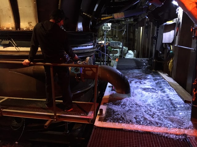 Aus einem Rohr fliessen grosse Mengen an Wasser in ein Becken, das mit einem Gitterrost abgedeckt ist. Aus einem Rohr fliessen grosse Mengen an Wasser in ein Becken, das mit einem Gitterrost abgedeckt ist.