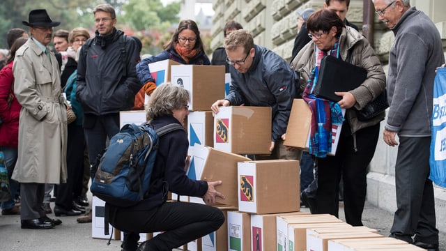 Leute mit vielen Kartons die mit den Kantonswappen gekennzeichnet sind, stehen vor dem Bundeshaus. Leute mit vielen Kartons die mit den Kantonswappen gekennzeichnet sind, stehen vor dem Bundeshaus.