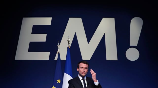 Macron spüricht, dahinter Frankreich- und EU-Flagge sowie in Grossbuchstaben «EM!». Macron spüricht, dahinter Frankreich- und EU-Flagge sowie in Grossbuchstaben «EM!».